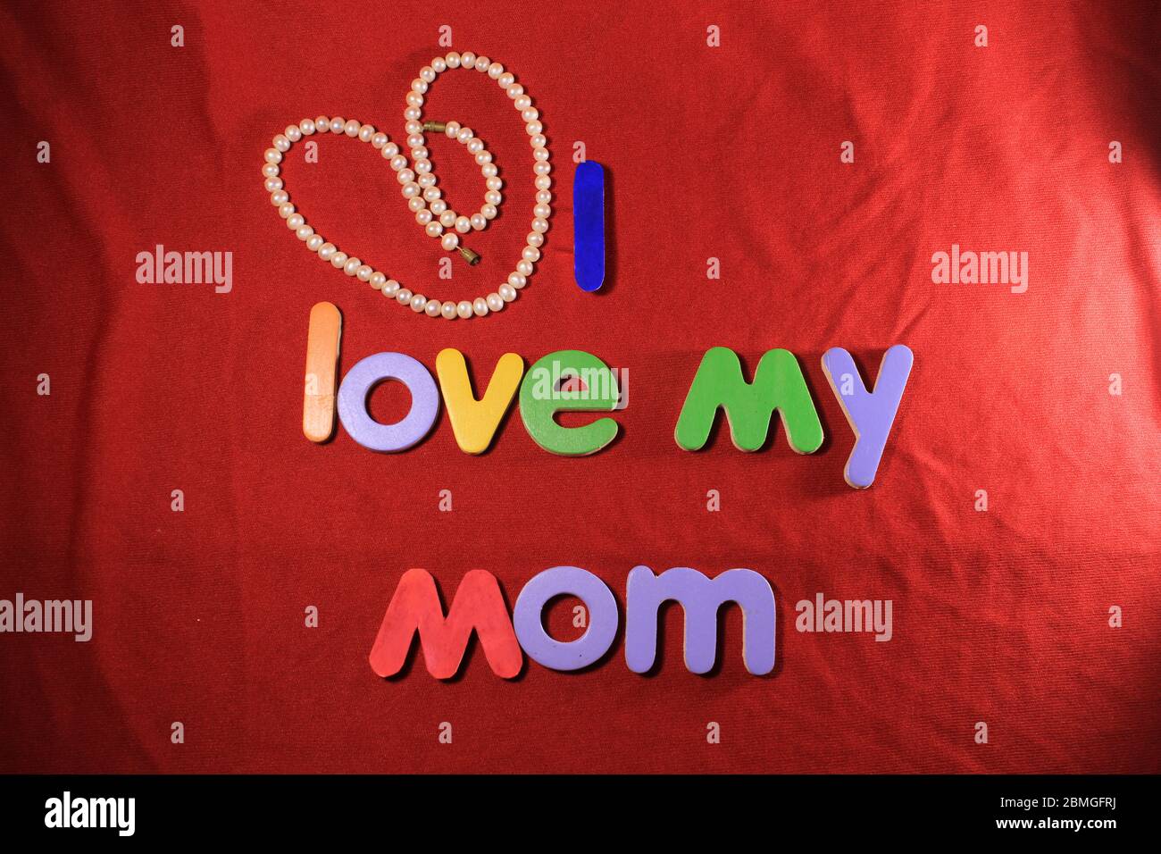 Lettere colorate con amo la mia mamma isolato su fondo di tessuto rosso. Amo la mia mamma con lettere colorate e cuore rosso per la giornata delle madri. Foto Stock