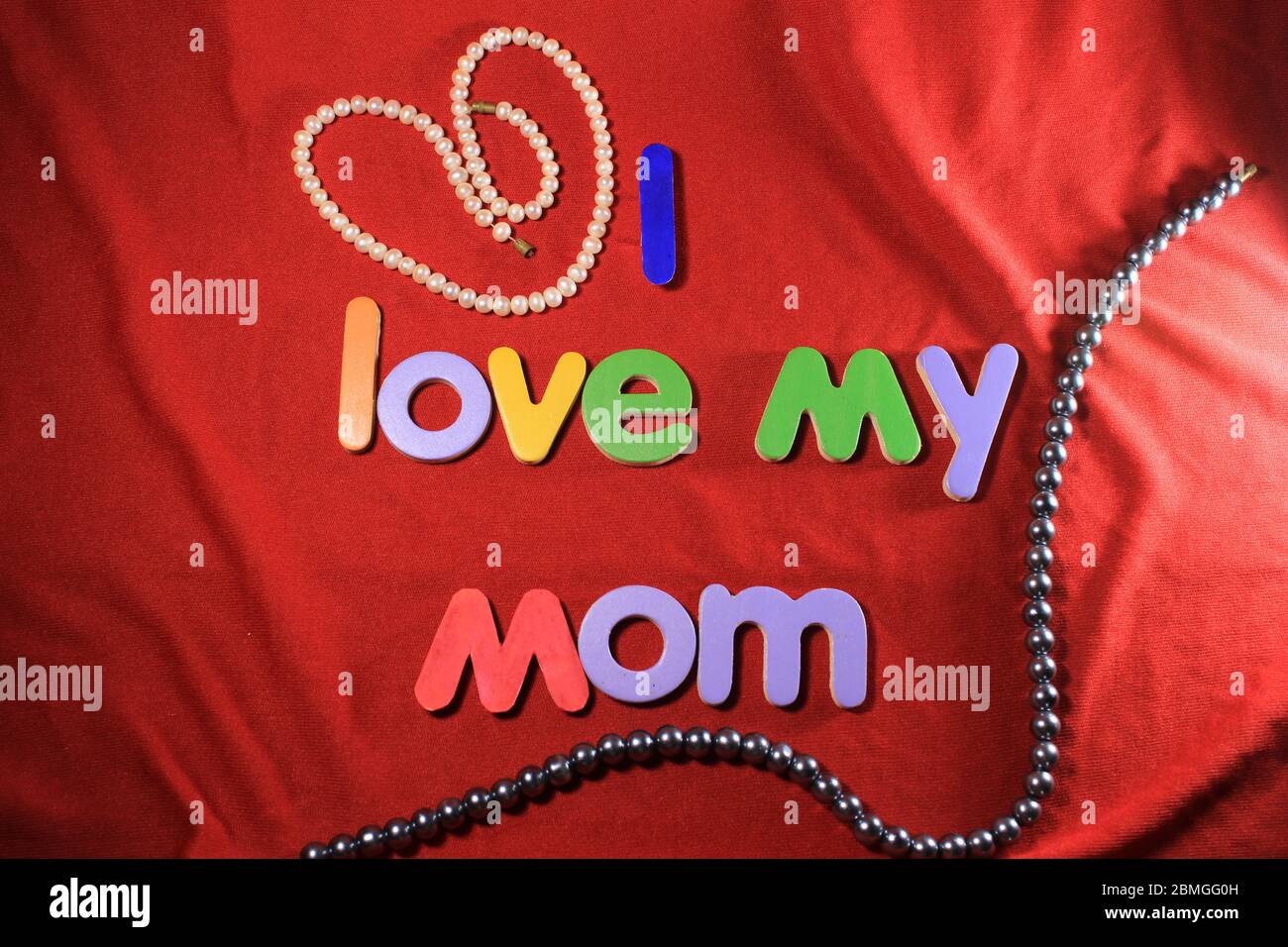 Lettere colorate con amo la mia mamma isolato su fondo di tessuto rosso. Amo la mia mamma con lettere colorate e cuore rosso per la giornata delle madri. Foto Stock