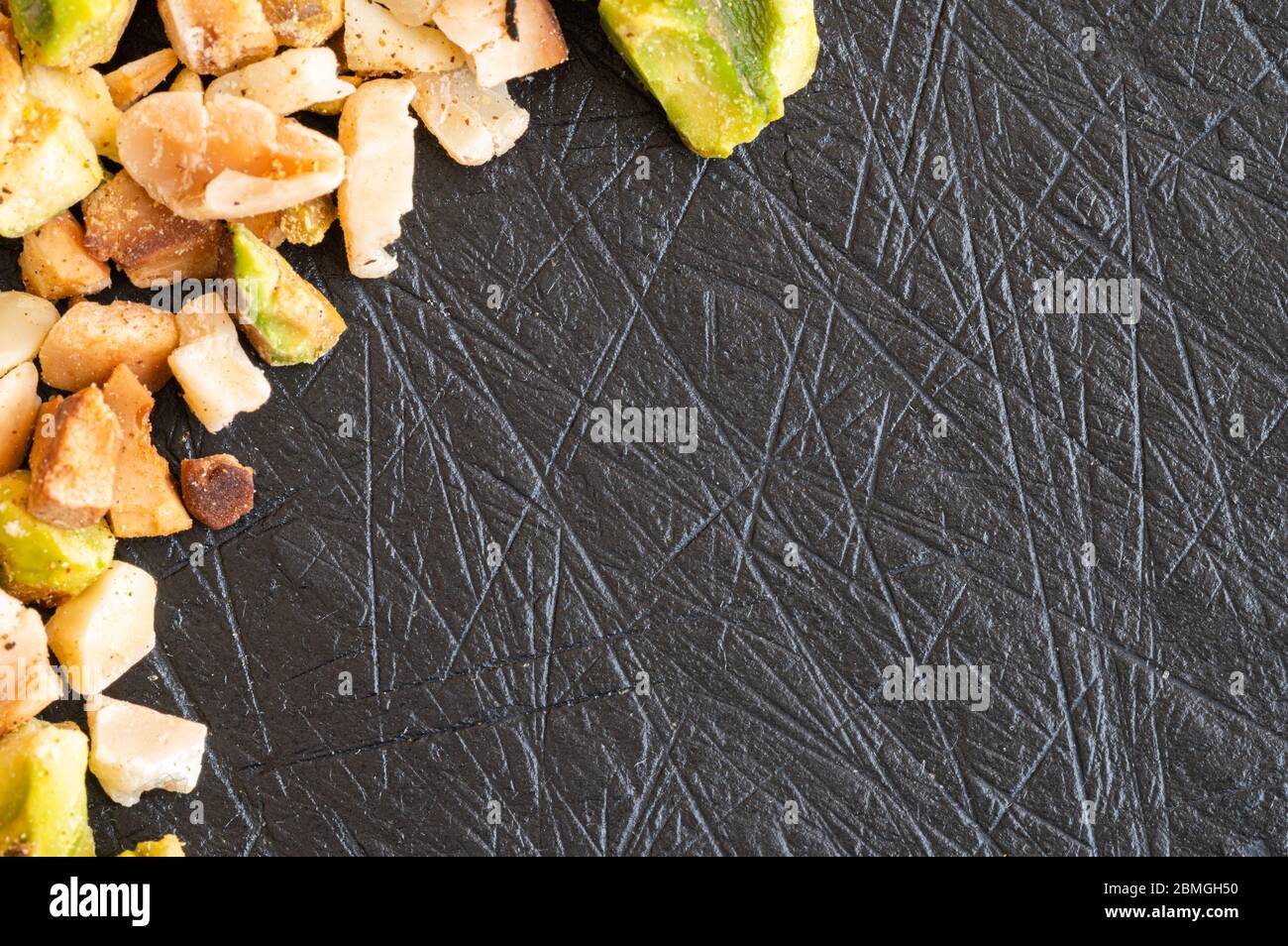 Tostate il pistacchio e le nocciole tritate su una tavola nera con spazio per il testo Foto Stock