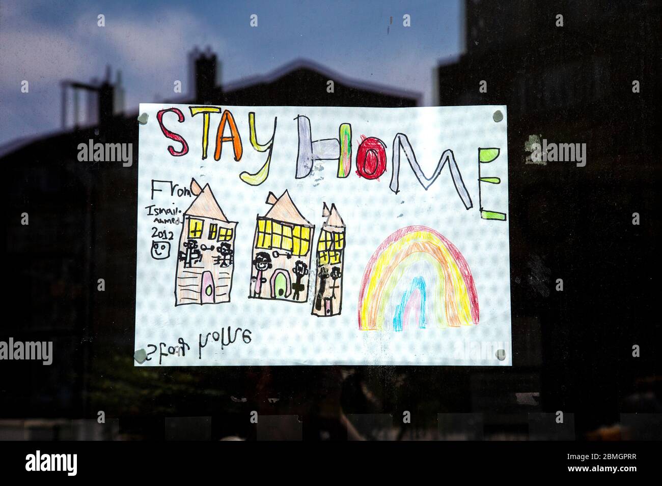 9 maggio 2020, Londra, Regno Unito - stay home segno disegnato da un bambino appeso alla porta di una farmacia a Stepney Foto Stock