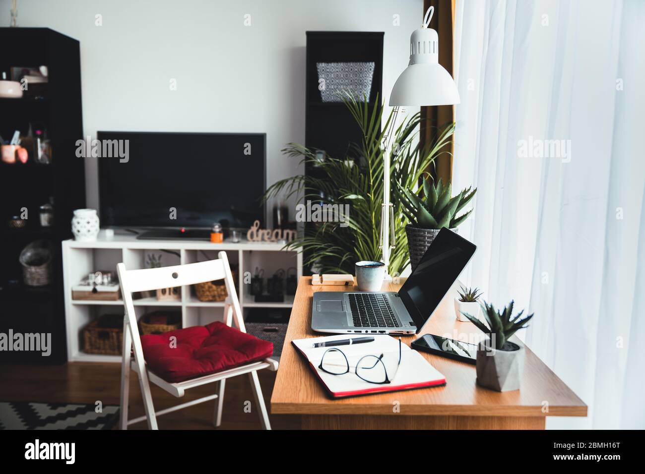 Benvenuti nel mio ufficio domestico: Un'immagine di tecnologia tagliata e un notebook su una scrivania in un ufficio domestico vuoto durante il giorno. Concetto di lavoro da casa Foto Stock
