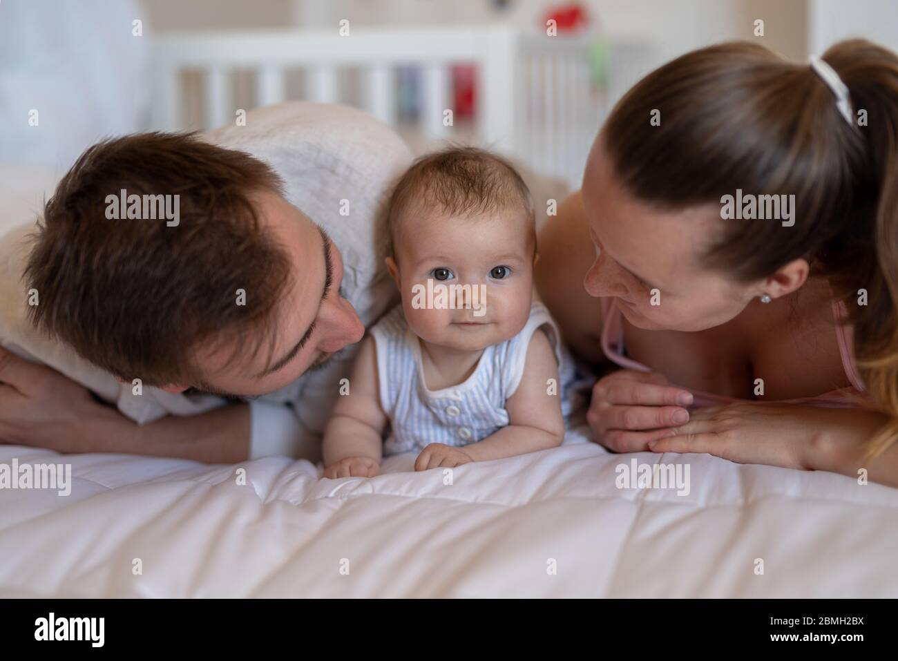 Coppia snuggle con la loro figlia bambino sul divano Foto Stock