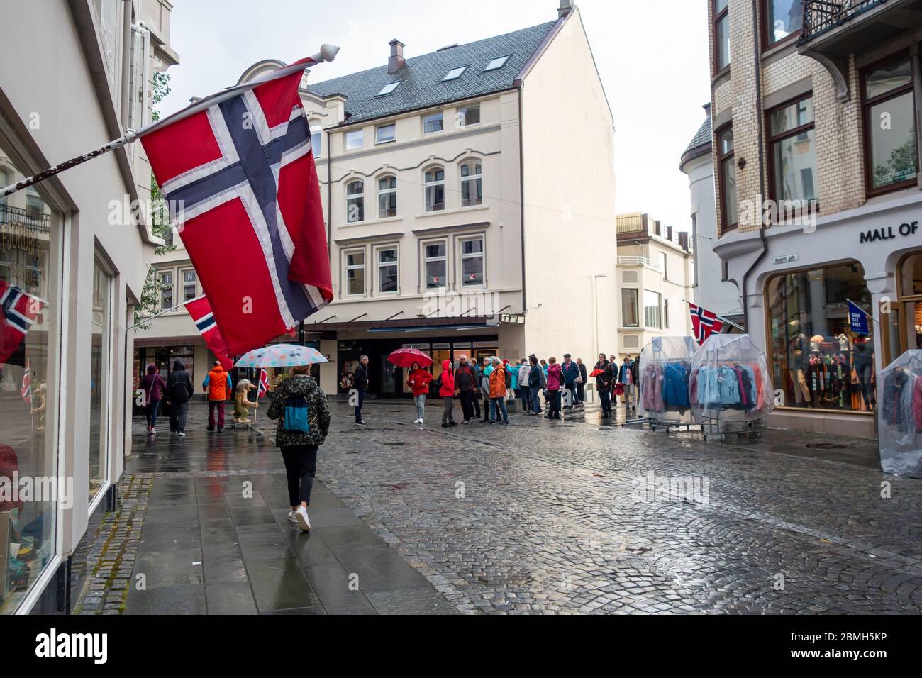 Alesund, Norvegia - 17 agosto 2019: Vista della strada con bandiera norvegese appesa in un edificio, con persone nella strada nella città di Alesund Foto Stock