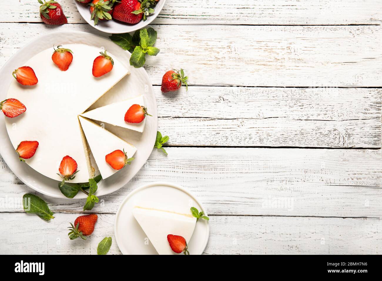 Piatto con gustosa cheesecake con fragole e menta su sfondo di legno. Vista dall'alto Foto Stock