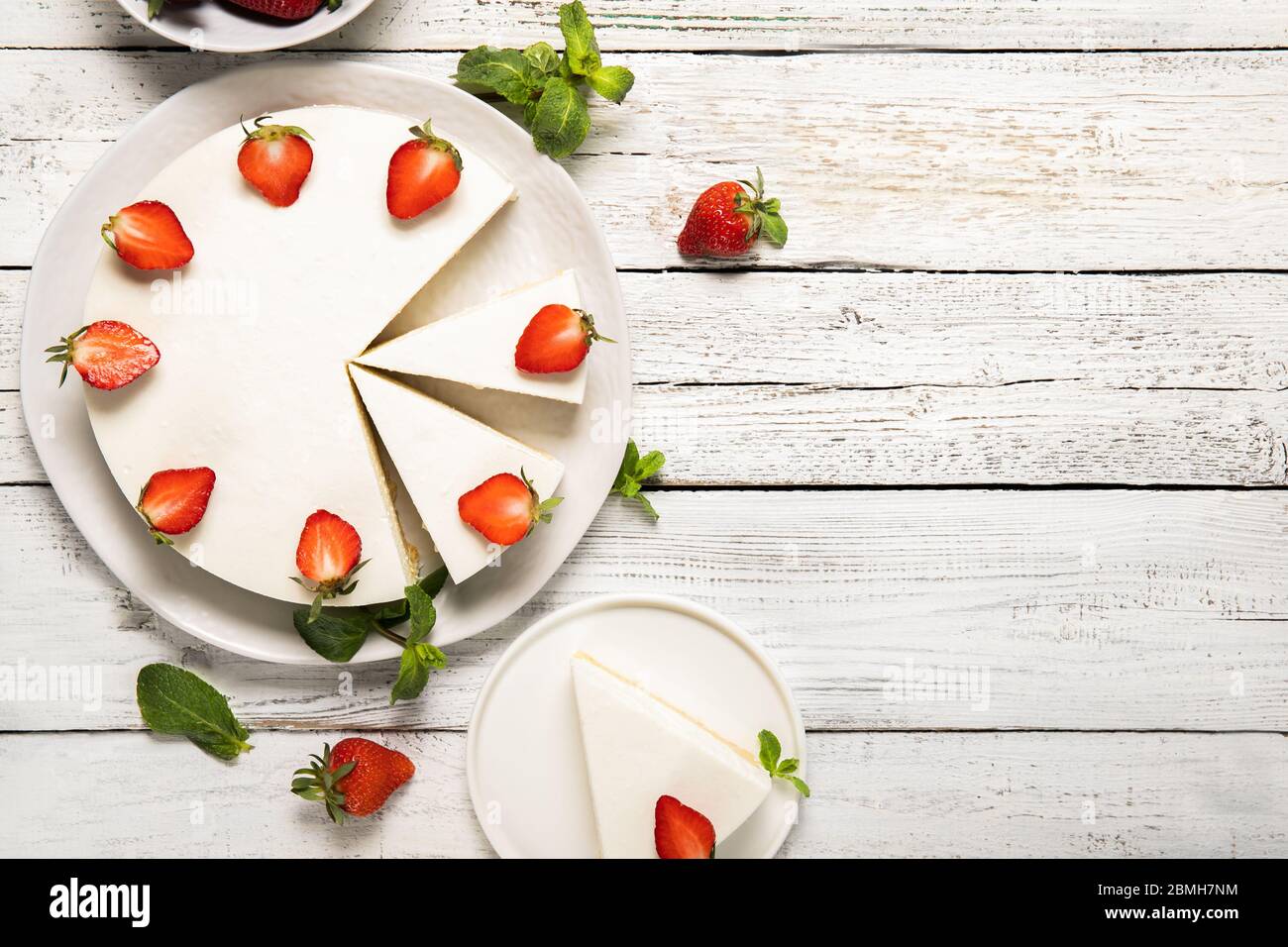 Piatto con gustosa cheesecake con fragole e menta su sfondo di legno. Vista dall'alto Foto Stock