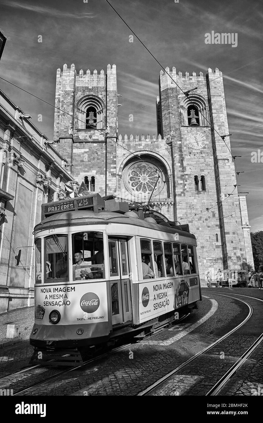 Un tram passa davanti alla cattedrale di Lisbona, nella zona della città vecchia di Lisbona, Portogallo. Foto Stock