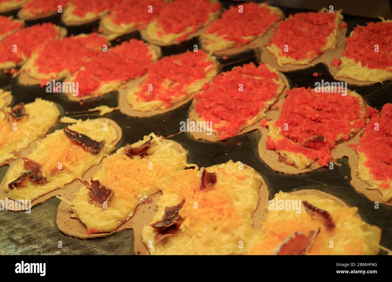 Fila di Crepes croccanti thailandesi chiamata Khanom Bueang, uno dei popolari Street food in Thailandia che viene cucinato su grande piatto Foto Stock