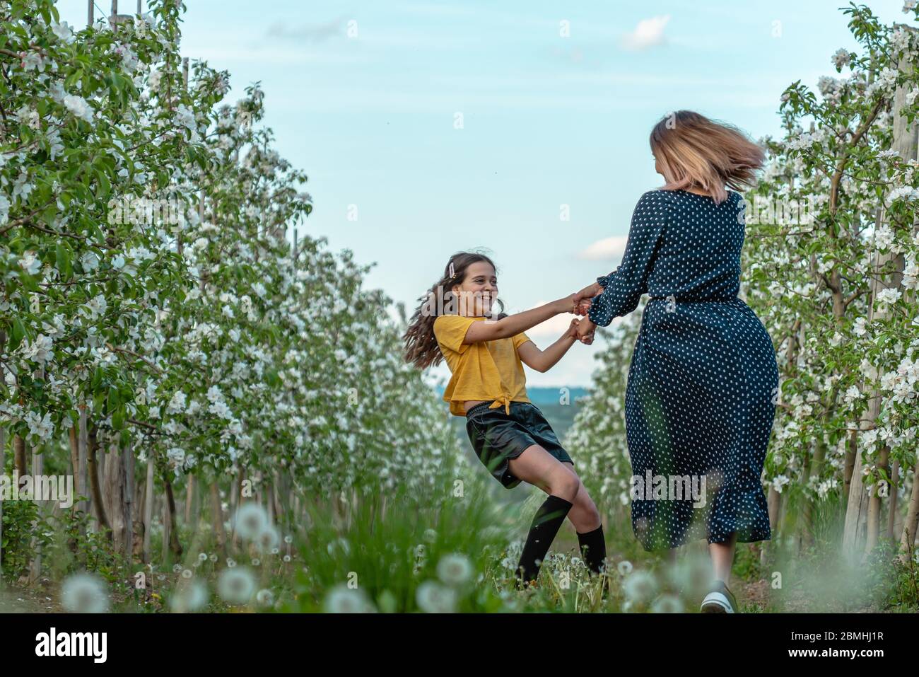 Famiglia felice, mamma e figlia che giocano insieme nel giardino fiorente Foto Stock