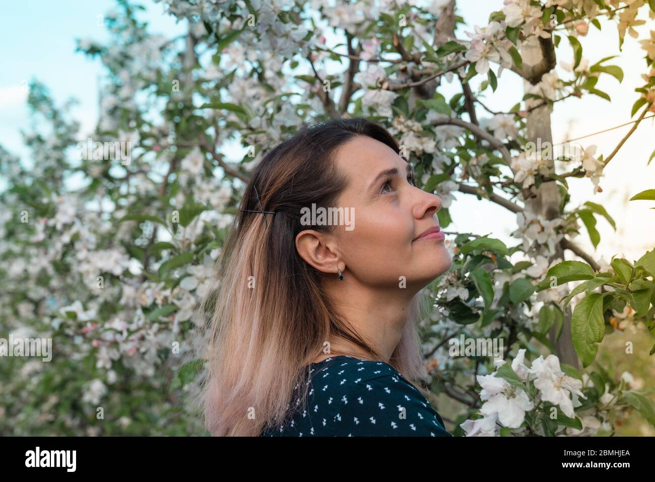 Giovane donna sognante tra giardino fiorente che trasudano all'angolo superiore destro Foto Stock