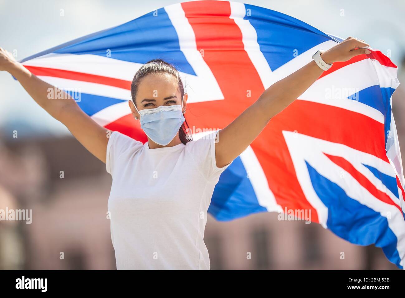 Donna in maschera facciale tiene una bandiera britannica durante la campagna Stay strong. Foto Stock