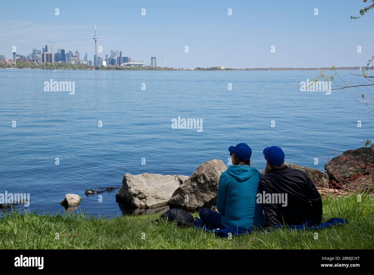 Toronto, Ontario / Canada - 05/21/2018: Coppia seduta sull'erba con Toronto cityscape come sfondo Foto Stock