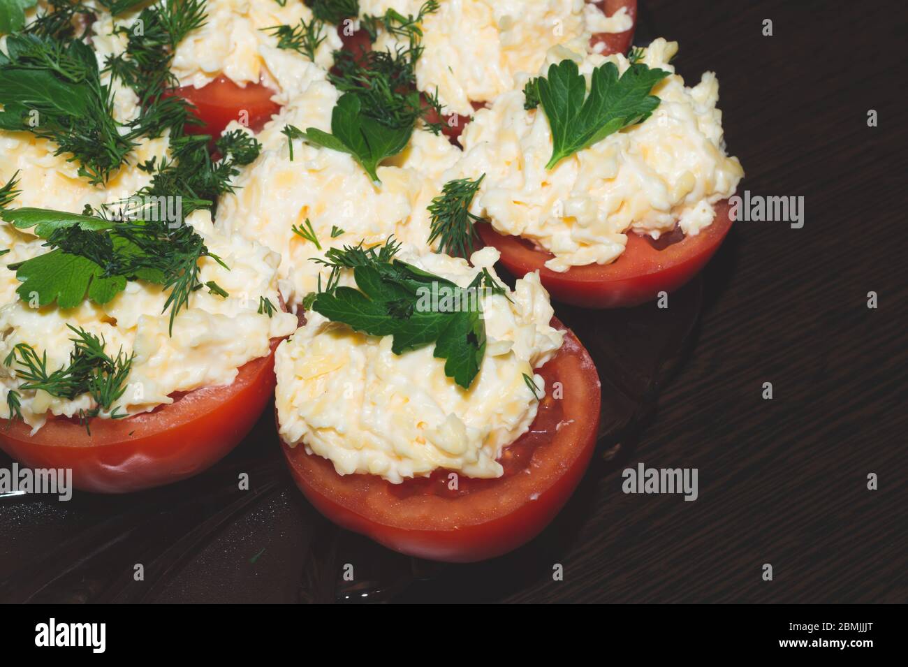 Pomodoro con formaggio e prezzemolo, antipasto di verdure, metà di pomodori con formaggio grattugiato Foto Stock