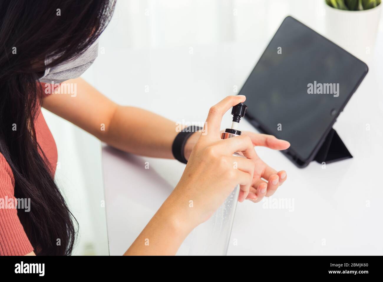 Asian Business giovane donna che lavora da casa ufficio ha quarantine malattia coronavirus o COVID-19 indossare una maschera protettiva e pulizia mani con s. Foto Stock