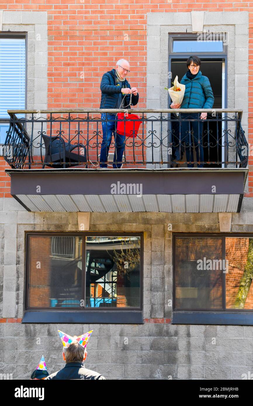 Amici che festeggiano il felice compleanno di un amico rispettando le distanze fisiche . Portarono un mazzo di fiori e cantarono una canzone . I fiori sono stati tirati in su in un secchio con una corda. Covid 19 Pandemic , Montreal Canada Foto Stock