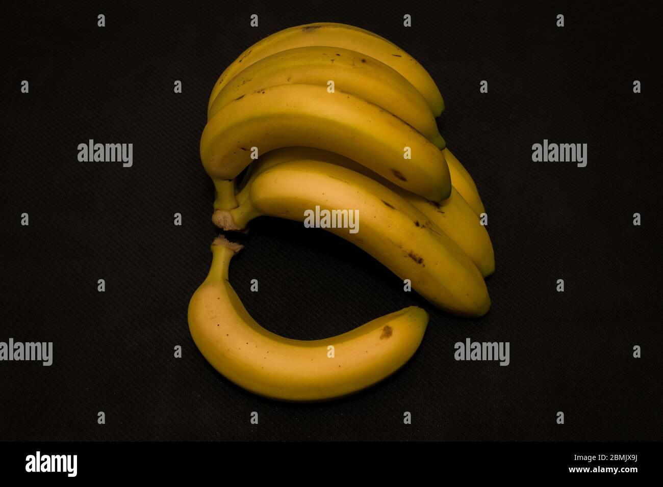 Banane gialle su terra nera scura Foto Stock