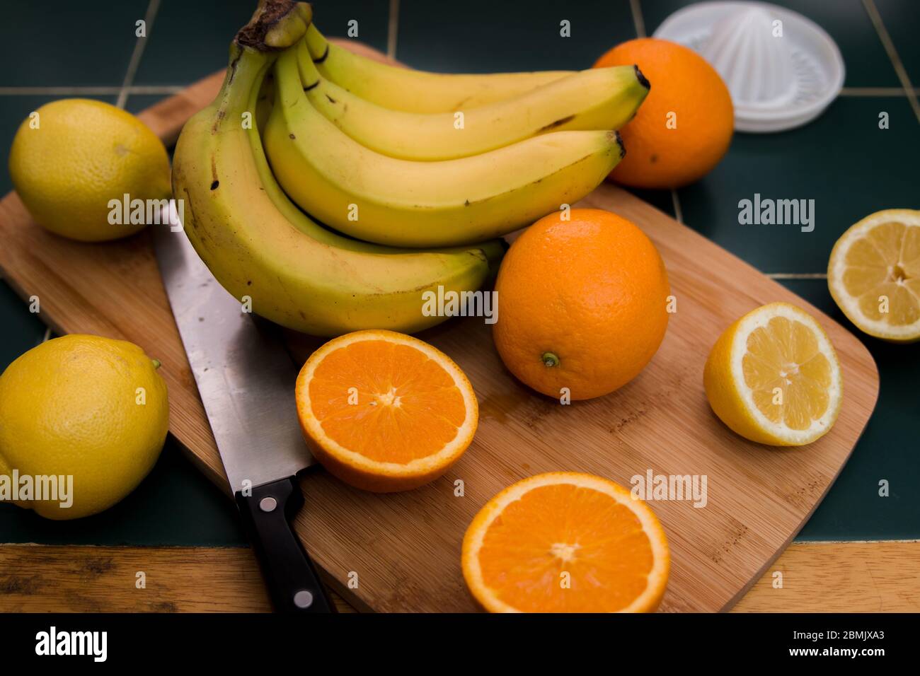 Arance, banane e limoni su un tagliere di legno. Tagliare arance e limoni Foto Stock