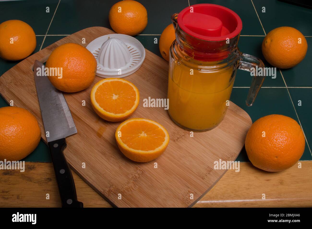 Vista isometrica delle arance su tagliere di legno con coltello e succo d'arancia Foto Stock