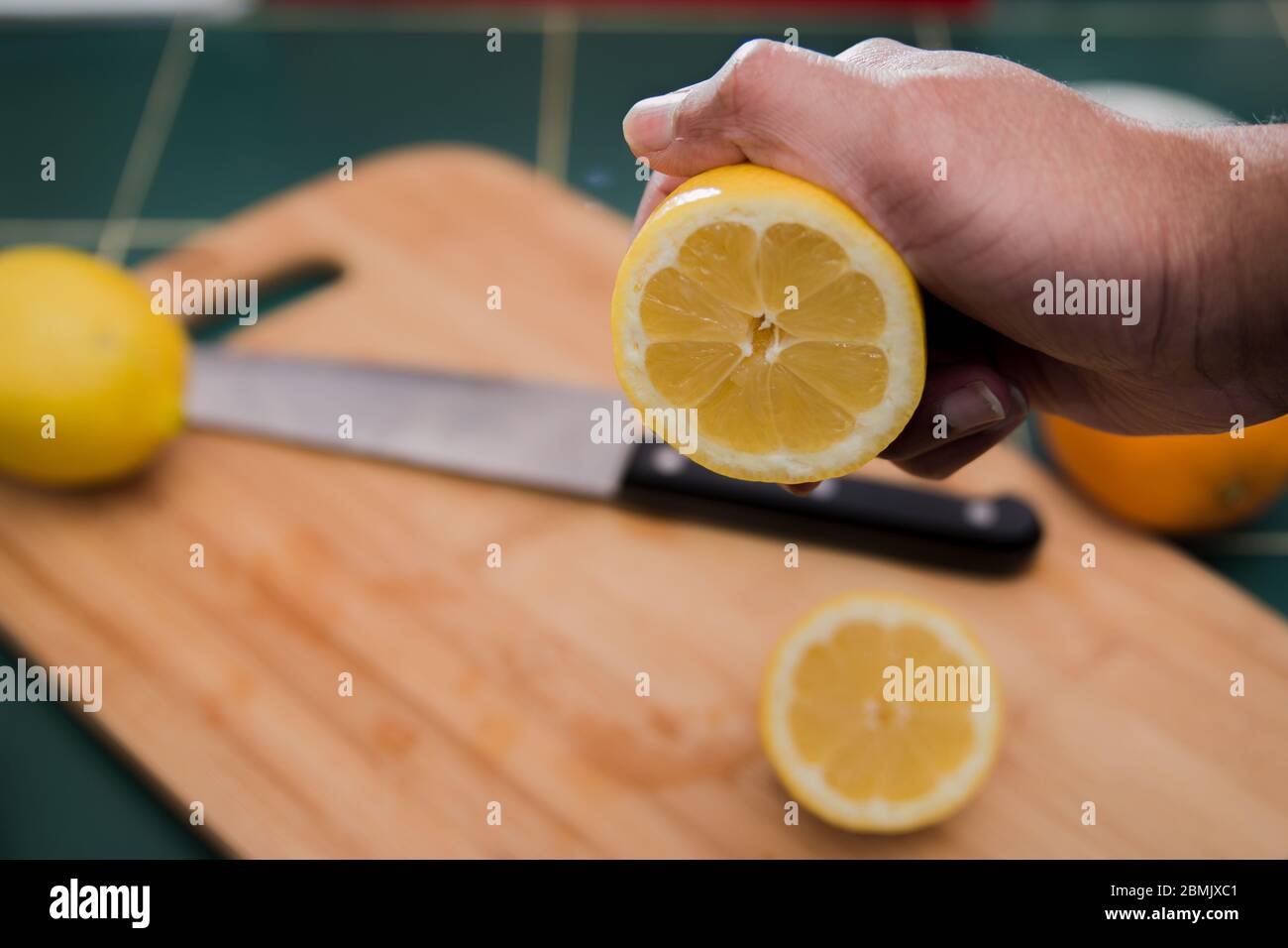 Limone appena tagliato che sta per essere spremuto con una mano dell'uomo Foto Stock