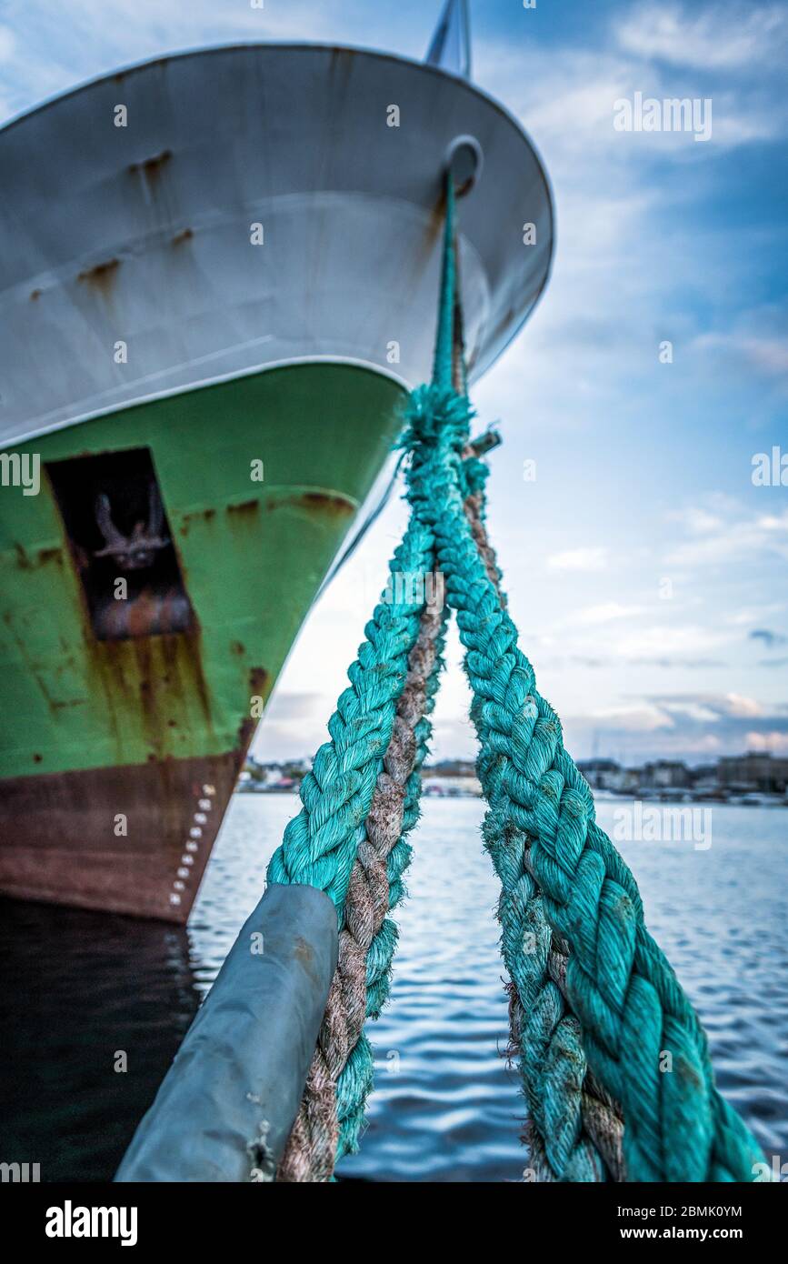 Corde di ormeggio verdi tese tra il molo e una nave lungo il porto Foto Stock