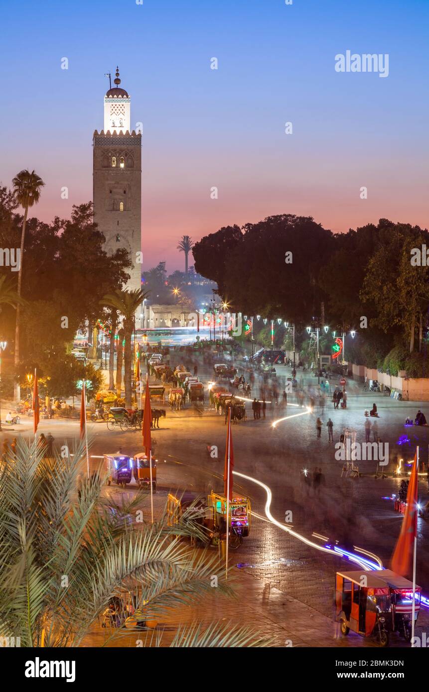 Il minareto della moschea Kasbah nella trafficata piazza Jemaa El Fnaa al tramonto da un patio a Marrakech, Marocco Marrakesh-Safi. Foto Stock