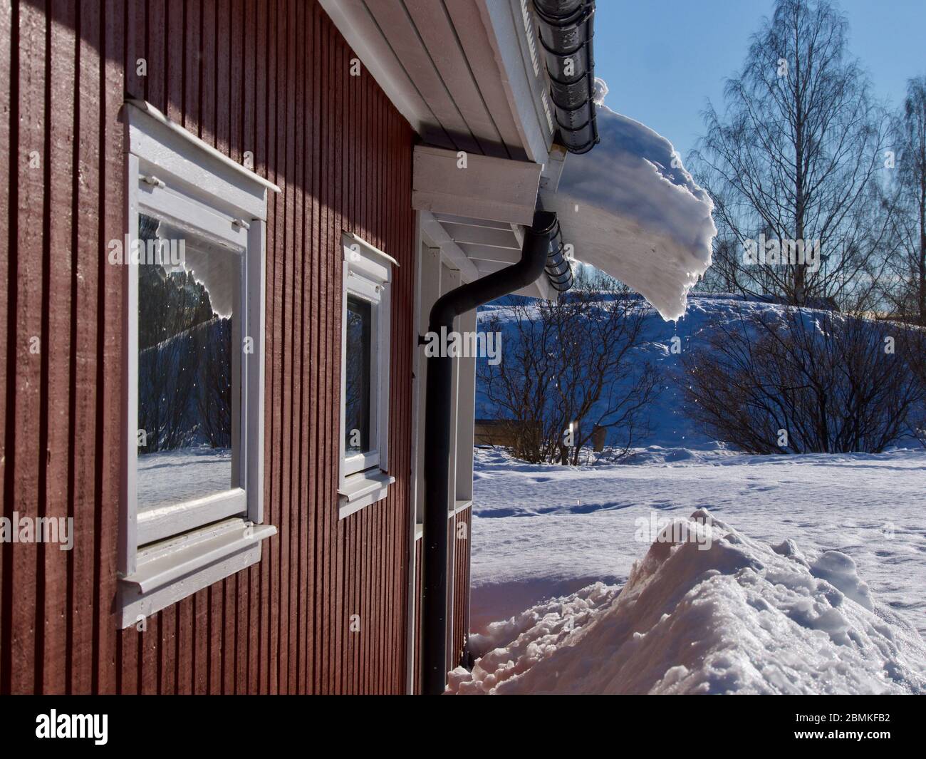 Ghiaccioli sulla visiera del tetto di casa di legno in primavera in Svezia Foto Stock