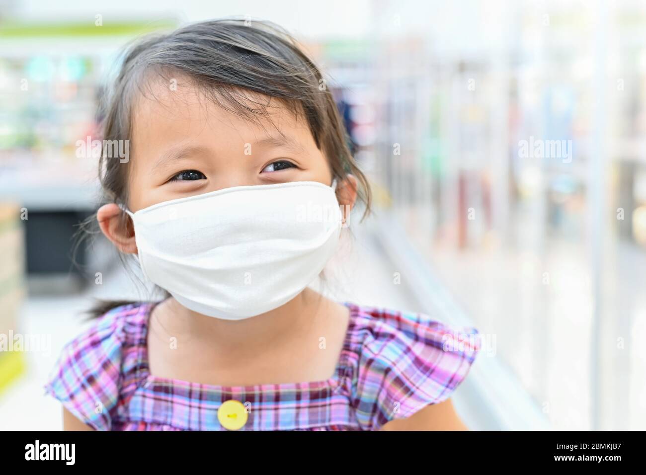 Bambina ha maschera di tessuto proteggere se stessa da Coronavirus quando il bambino andare al supermercato con la madre dopo supermercato aperto di nuovo, bambino con una maschera Foto Stock