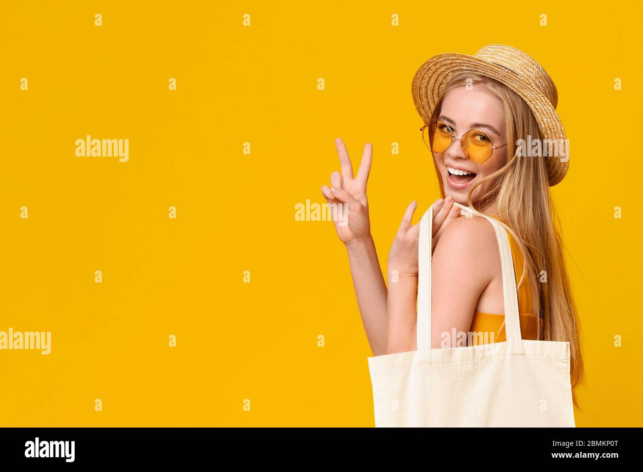 Elegante ragazza con cappello e occhiali da sole in paglia che mostra la pace Gesture Foto Stock