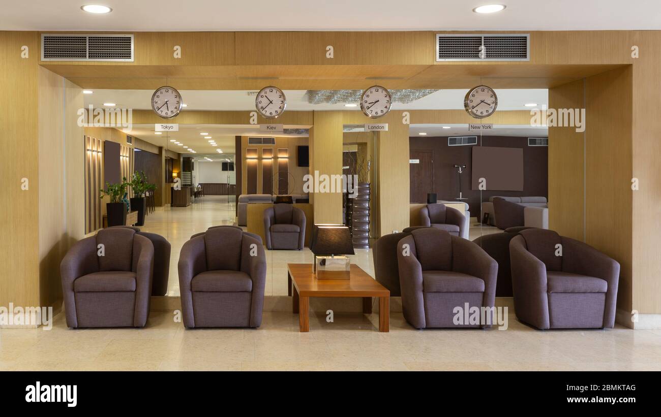 Lobby dell'hotel con poltrone e orologi marroni Foto Stock