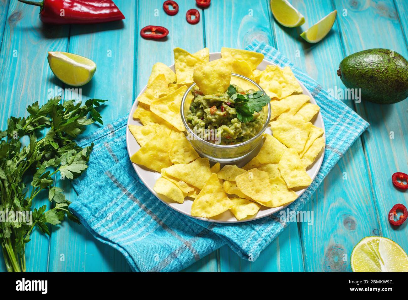 Nachos. Tortilla chips con Guacamole su sfondo di legno blu. Foto Stock