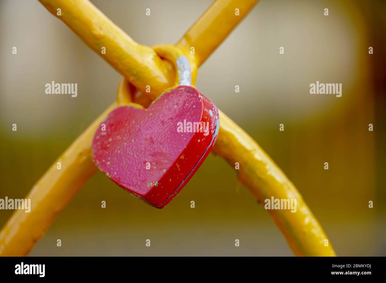 Lucchetto rosso a forma di cuore. Cuore metallico sulla recinzione. Simbolo di amore, concetto romantico. Foto Stock
