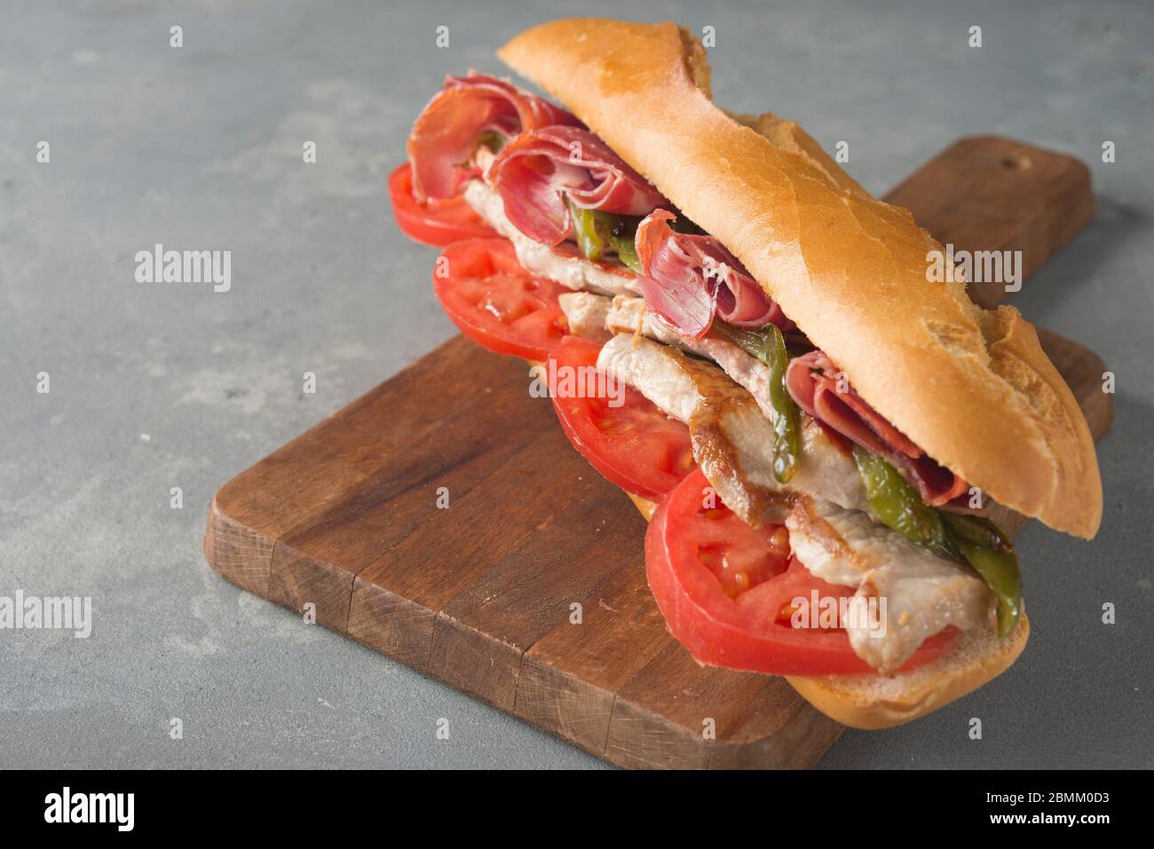 Sandwich Serranito tipico dell'Andalusia con prosciutto, pepe e lombo di maiale alla griglia Foto Stock