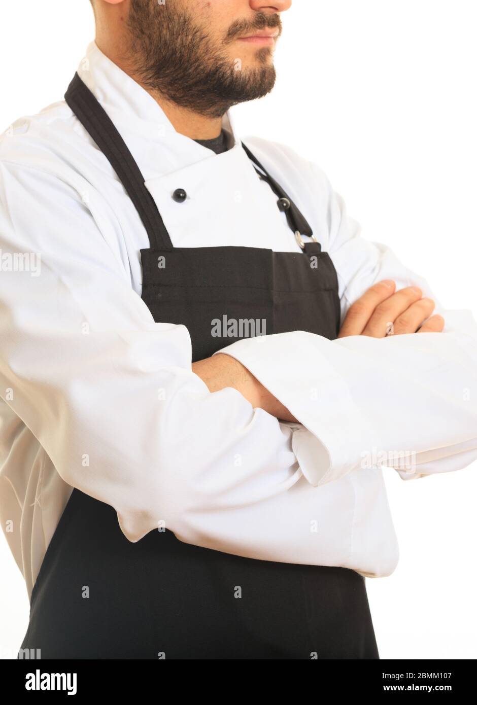 Chef con uniforme bianca e grembiule nero in piedi con mani incrociate su sfondo bianco. Preparazione del menu del ristorante. Verticale verticale. Foto Stock