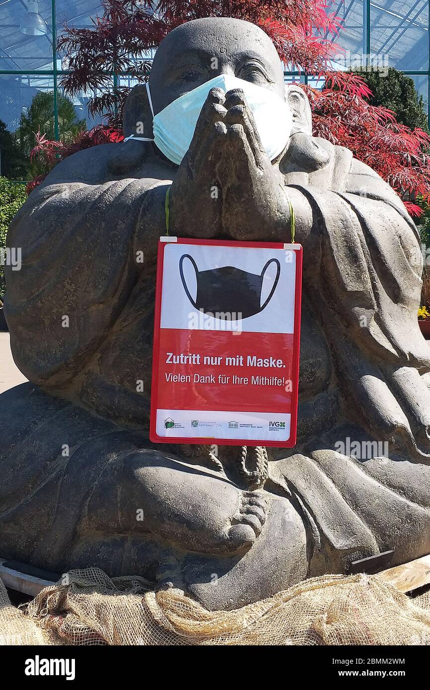 buddha gigante seduto in pietra che indossa una maschera gigante sta mettendo´s mani insieme per compiacere di indossare una maschera facciale Foto Stock