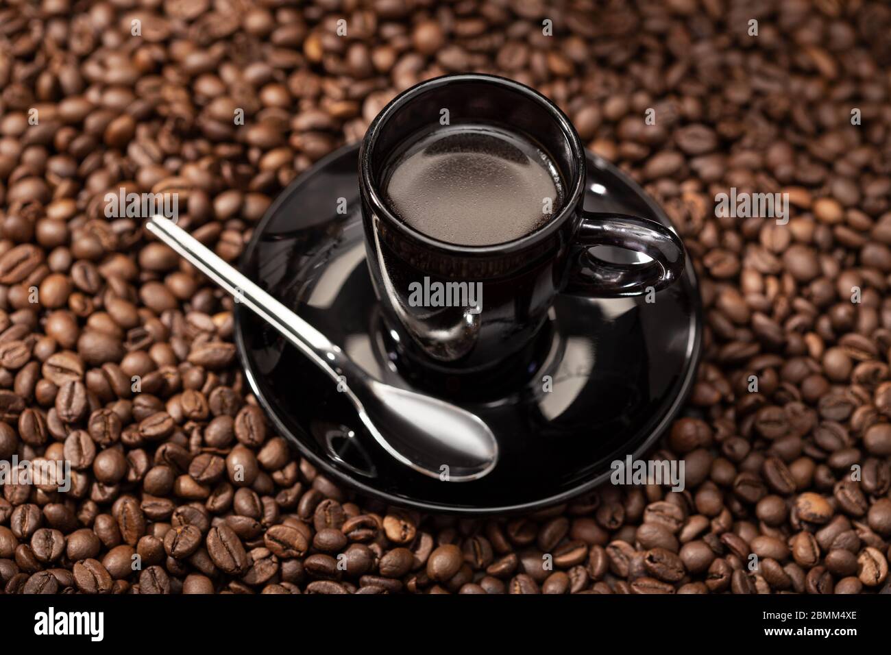 Caffè espresso in tazza nera e fagioli arrostiti. Caffè di fondo Foto Stock