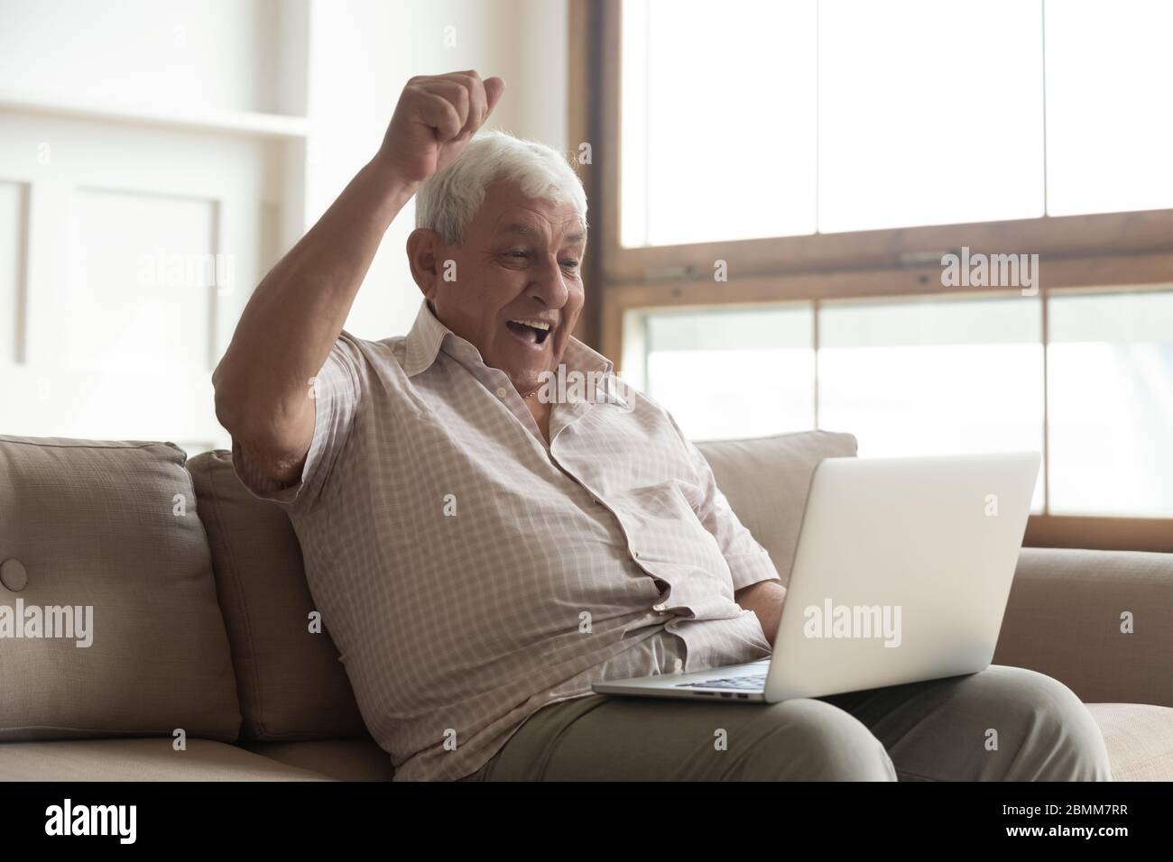 Felice uomo maturo vince lotteria online su notebook Foto Stock