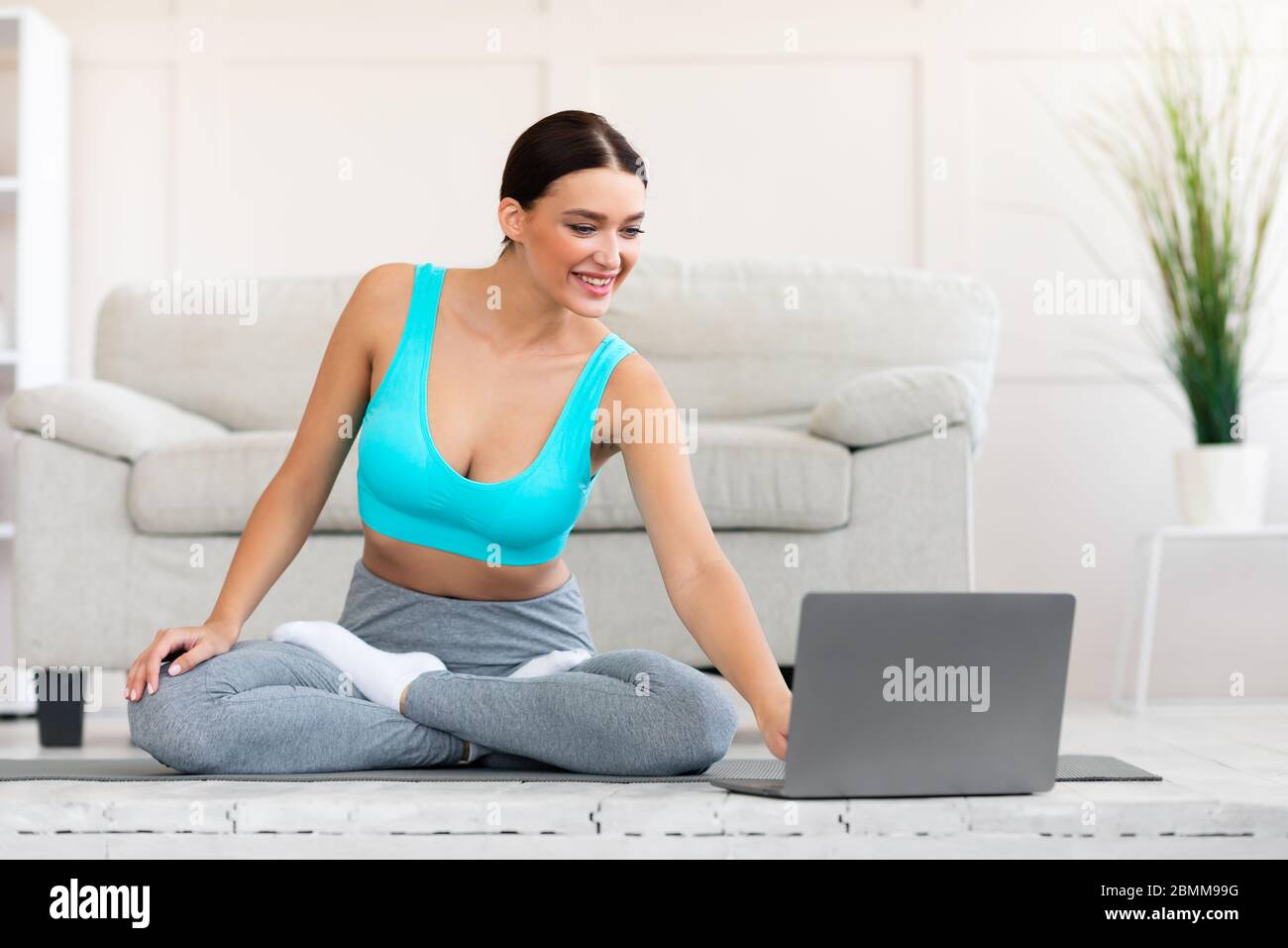 Donna sottile pratica yoga al laptop guardare i video online in interni Foto Stock