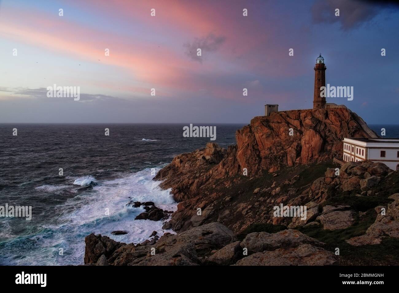 Faro di Cabo Vilan sulla costa galiziana in un tramonto colorato e con il mare in una rabbia. Il faro elettrico più antico della Spagna. Galicia, Spa Foto Stock