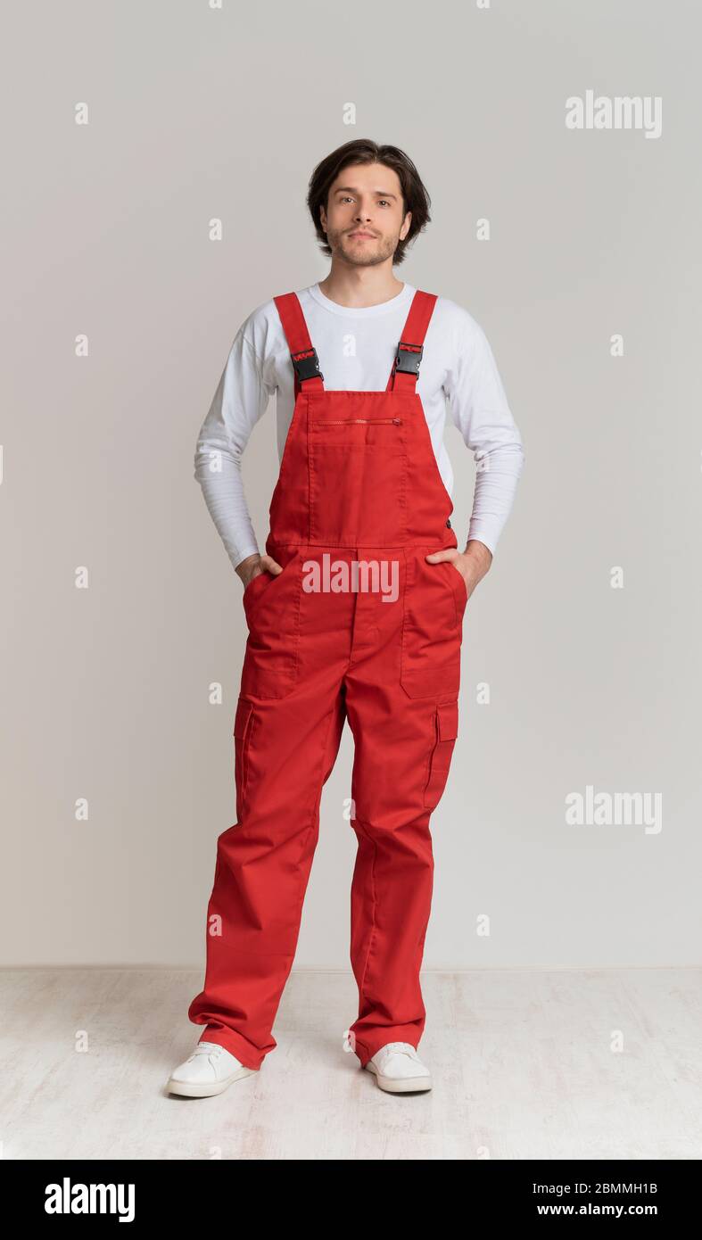 Ritratto di giovane uomo che indossa abiti da lavoro in posa su sfondo chiaro Foto Stock