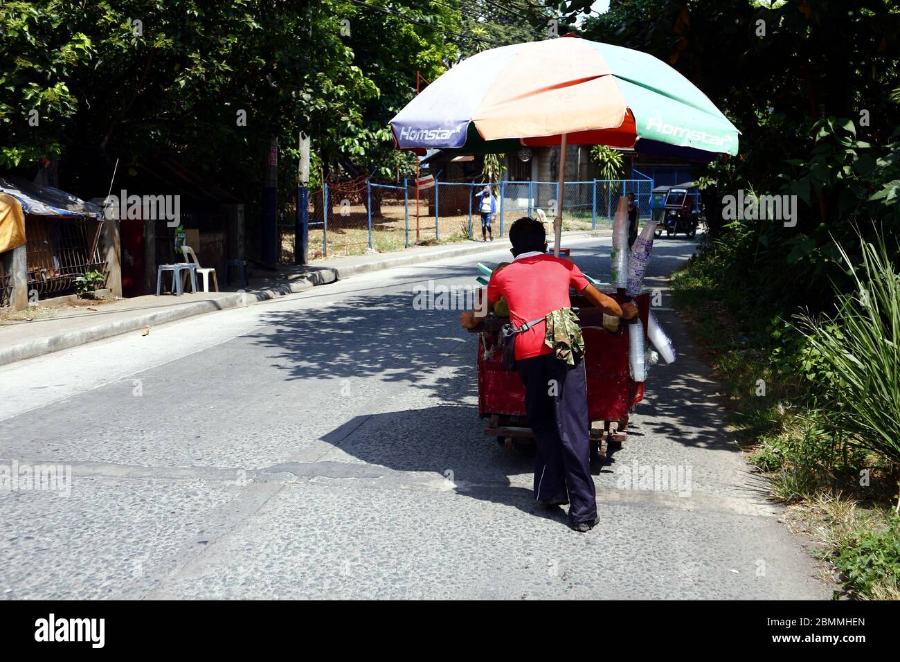 Antipolo City, Filippine - 7 maggio 2020: Venditore di strada che vende cocco e succo di cocco spingere il suo carrello alimentare sulla strada in una calda giornata estiva. Foto Stock