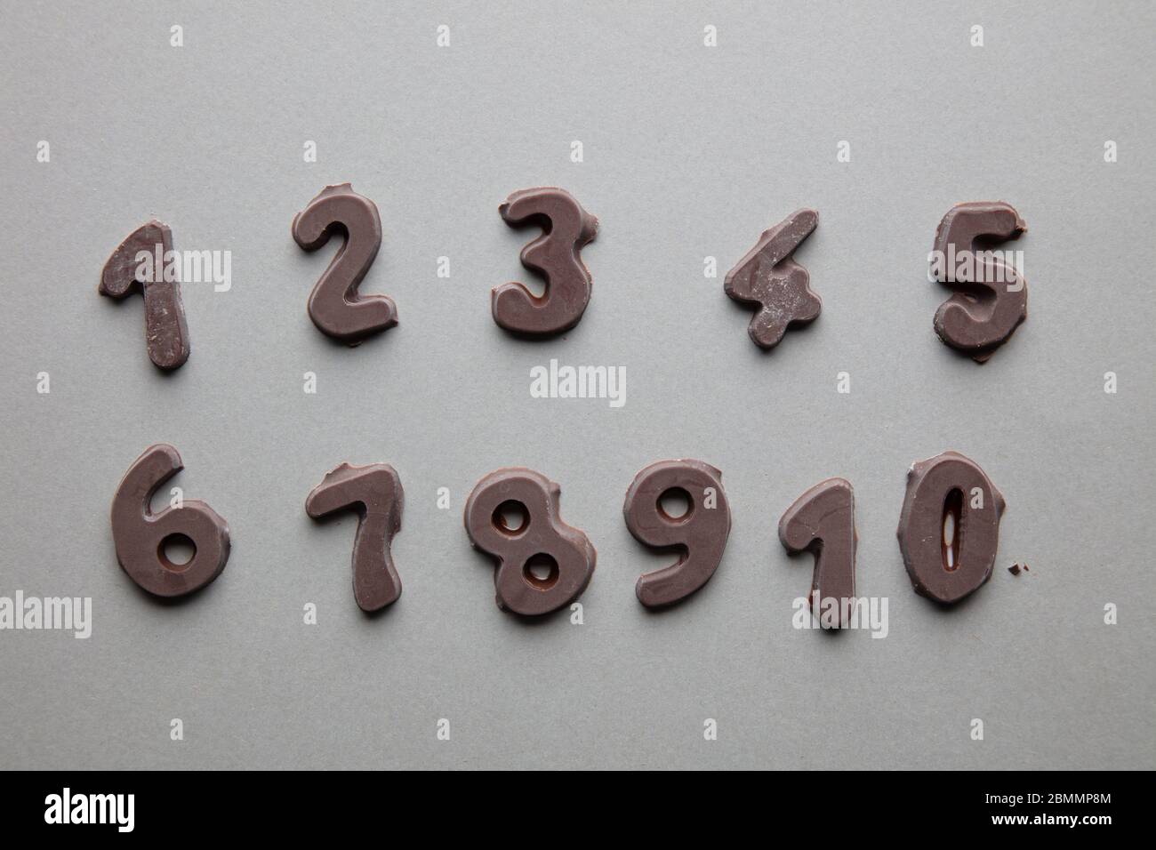 un'immagine artistica di numeri di cioccolato in ordine cronologico su sfondo grigio Foto Stock