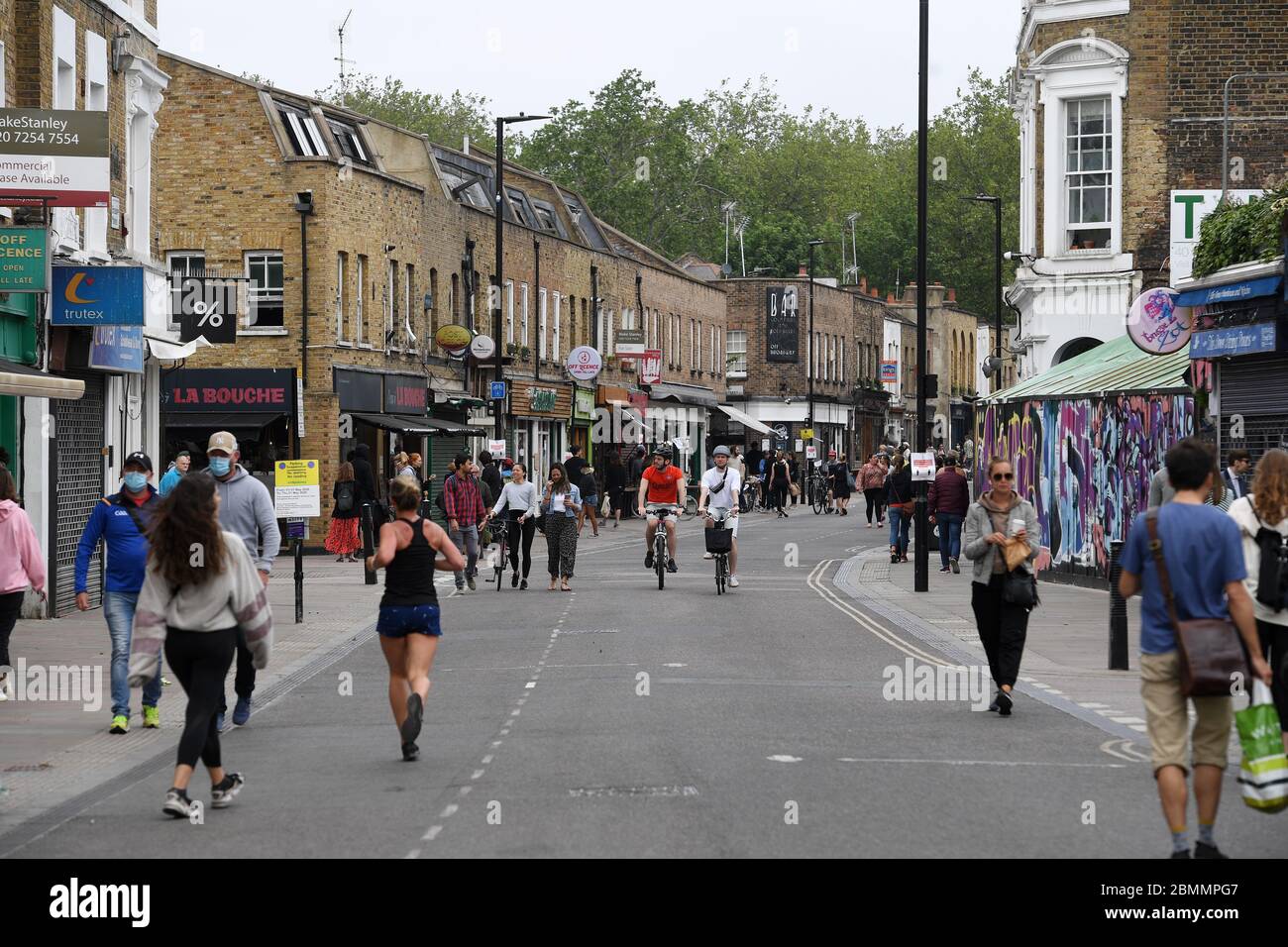 La gente cammina e pedala attraverso il Broadway Market di Londra, mentre il Regno Unito continua a fare il lock-down per contribuire a frenare la diffusione del coronavirus. Foto Stock