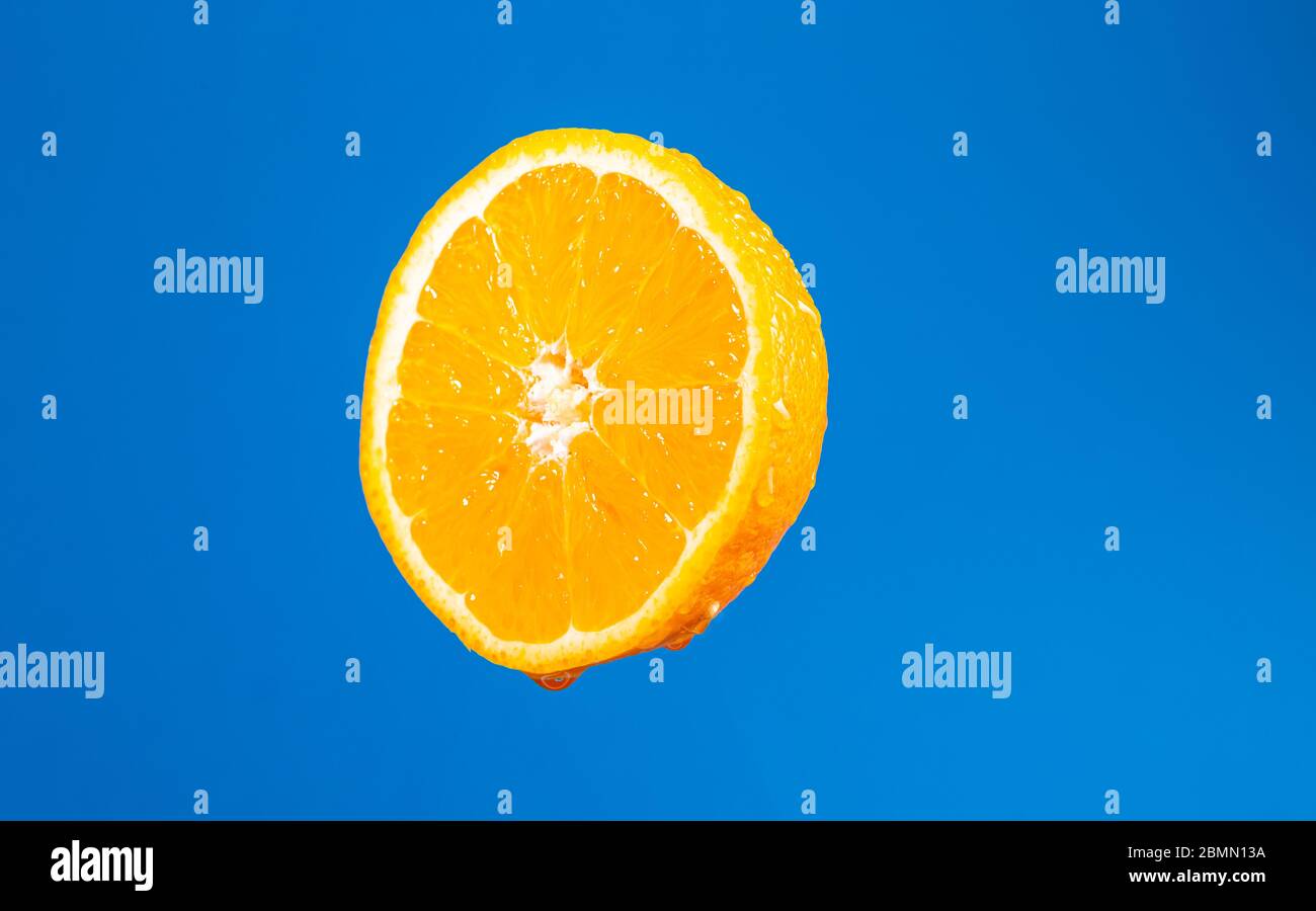 Arancia fresca. Frutta su sfondo blu. Taglia arancione. Gocce di succo di frutta. Piatto vegetariano. Citruses fresco. Gocce d'acqua sulla pelle. Frutta gocciolante Foto Stock