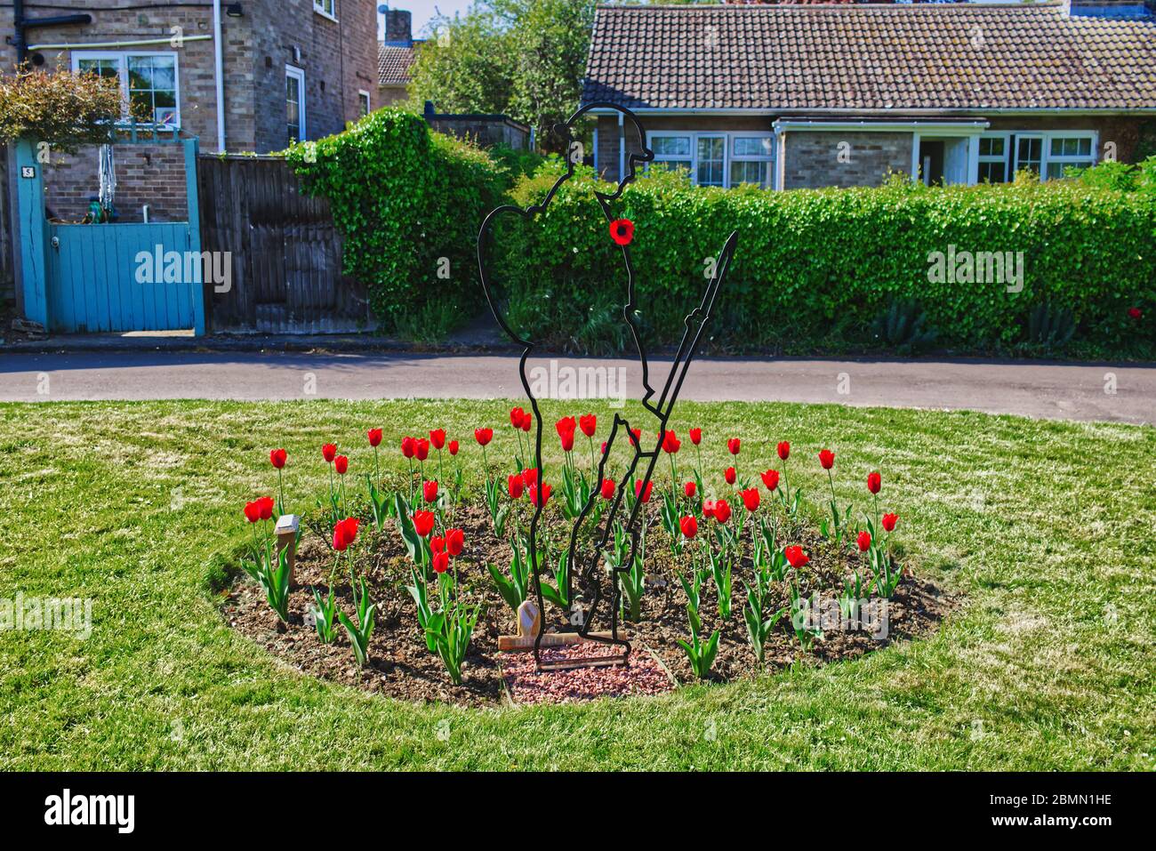 Bedfordshire villaggio verde con remembrance Tommy soldato silhouette circondato da tulipani rossi Foto Stock