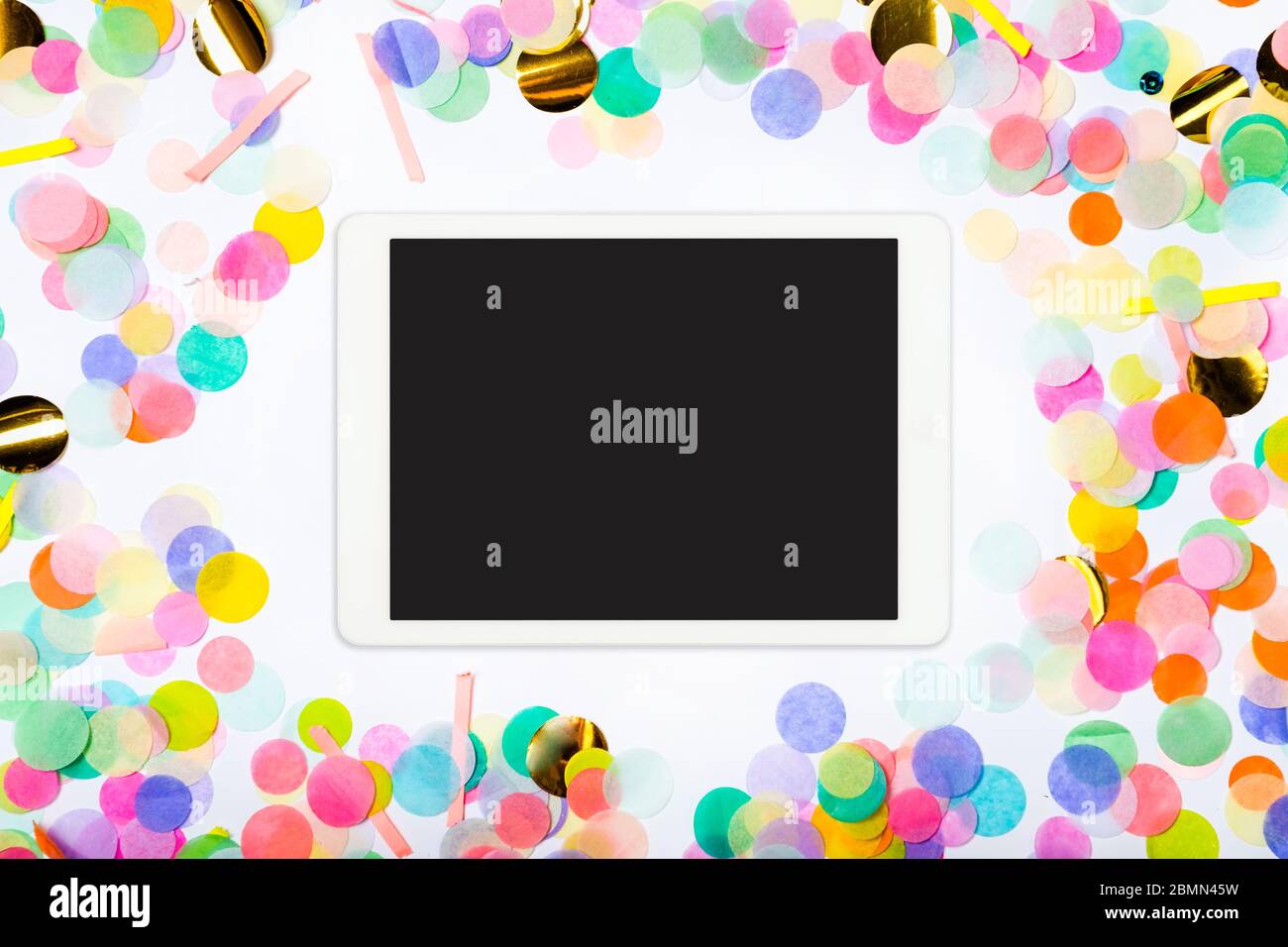 Touchpad con schermo vuoto su sfondo confetti colorato. Sfondo party a colori con pc touchscreen Foto Stock Touchpad con schermo vuoto su sfondo confetti colorato. Sfondo party a colori con pc touchscreen Foto Stock