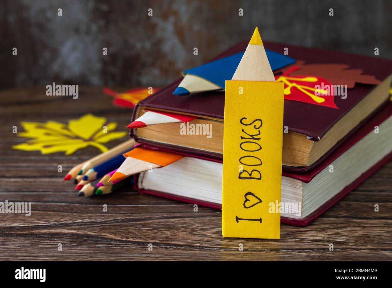 Bookmarks multicolore origami matita di carta con l'iscrizione che amo un  libro su un tavolo di legno. Benvenuti a scuola Foto stock - Alamy