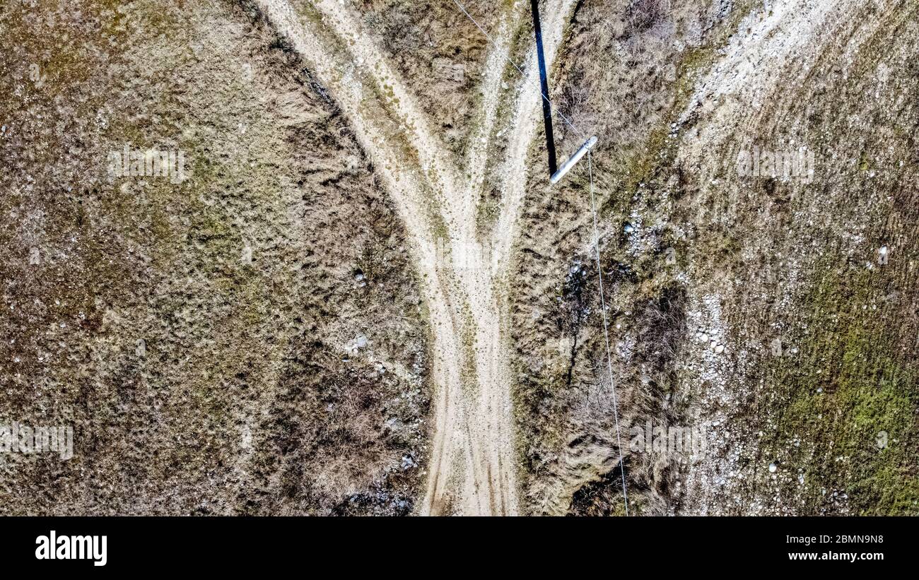 Veduta aerea di un crocevia tra due strade sterrate in aperta campagna. Un palo delinea una lunga ombra sul terreno. Foto Stock
