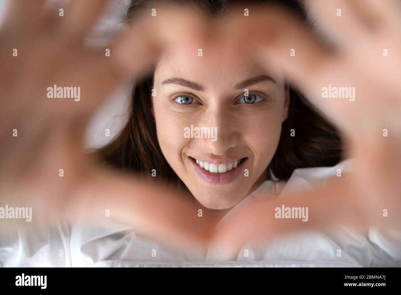 Donna risvegliata che mostra con le mani forma del cuore vista dall'alto Foto Stock