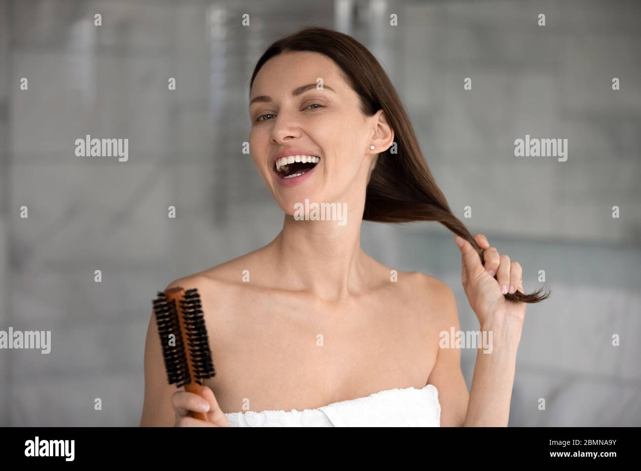 Donna ritratto con testa che tiene la spazzola pettinandola forte e sana capelli Foto Stock