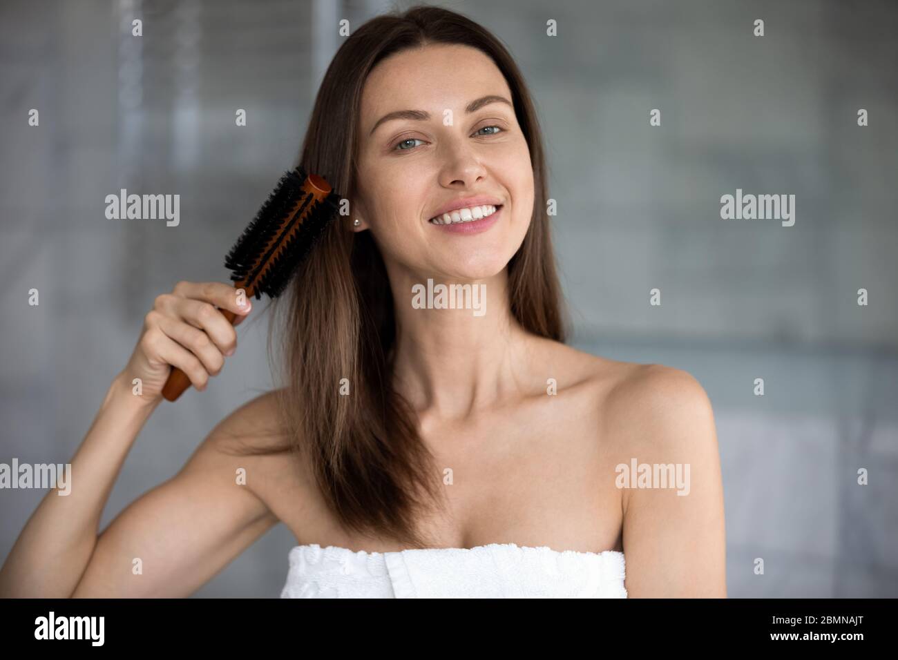 Donna dopo la doccia pettinando i suoi capelli marroni sani Foto Stock