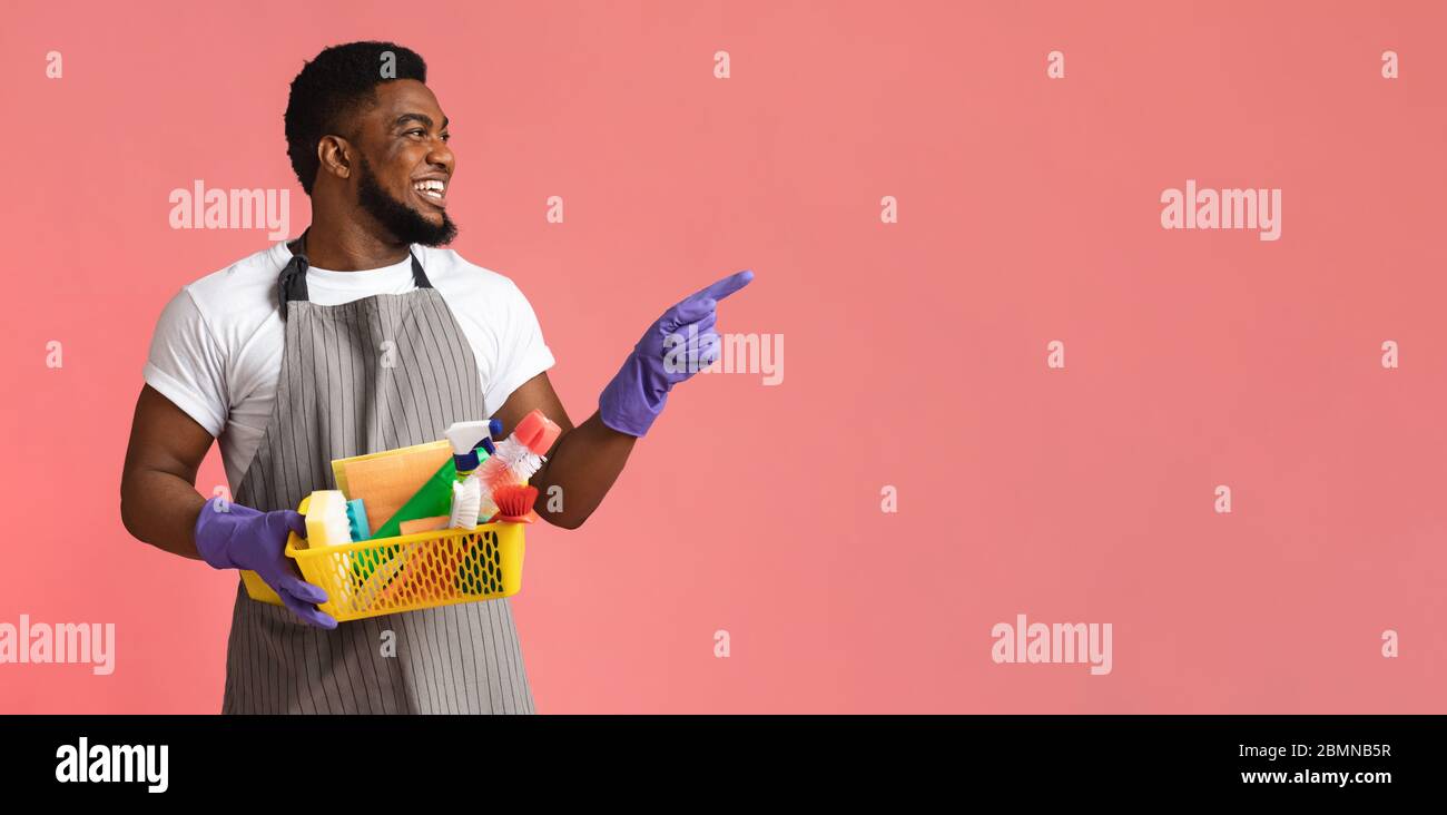 Pubblicità pulizia. Detergente maschio nero con forniture per la casa in mano che puntano da parte Foto Stock